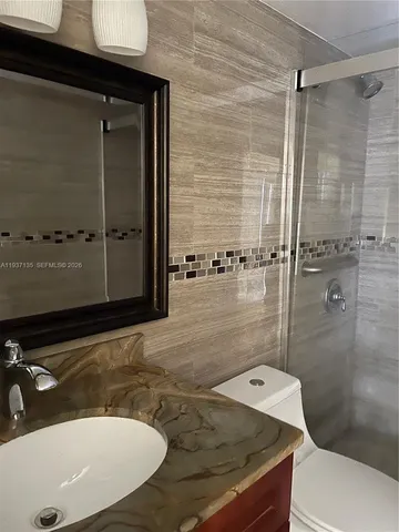 a bathroom with a sink shower and a mirror