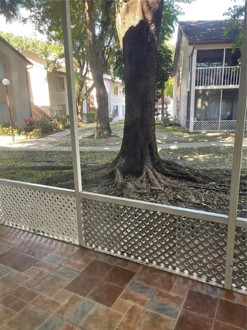 a side view of a house with a tree and wooden fence