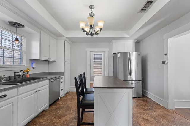 a kitchen with stainless steel appliances granite countertop a refrigerator a sink dishwasher a dining table and chairs with wooden floor