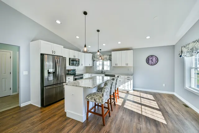 a kitchen with stainless steel appliances granite countertop a refrigerator a microwave a stove and a wooden floors