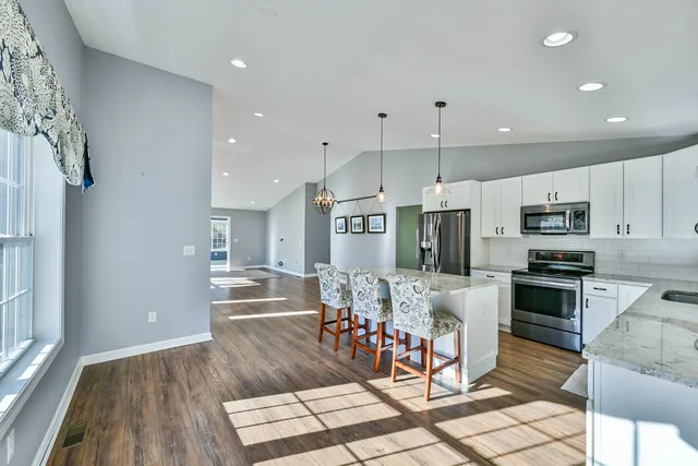a view of a kitchen with kitchen island stainless steel appliances refrigerator stove microwave and cabinets