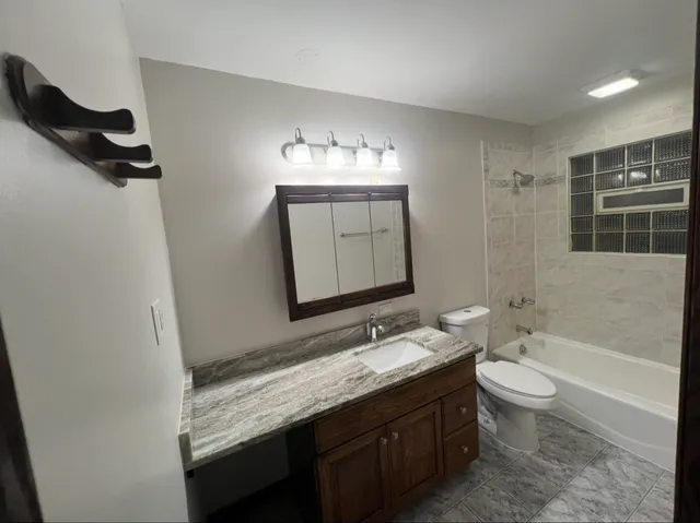 a view of an empty room with wooden floor and a ceiling fan
