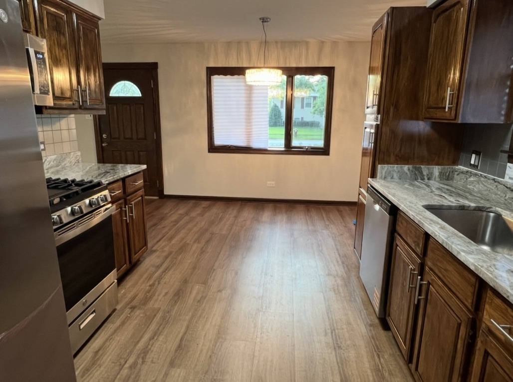 3529 Carpenter Street Steger, IL 60475 - Photo 2 of 20 a kitchen with granite countertop a stove a sink and a wooden floors