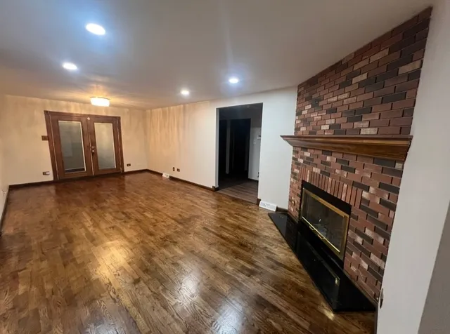 an empty room with wooden floor fireplace and windows