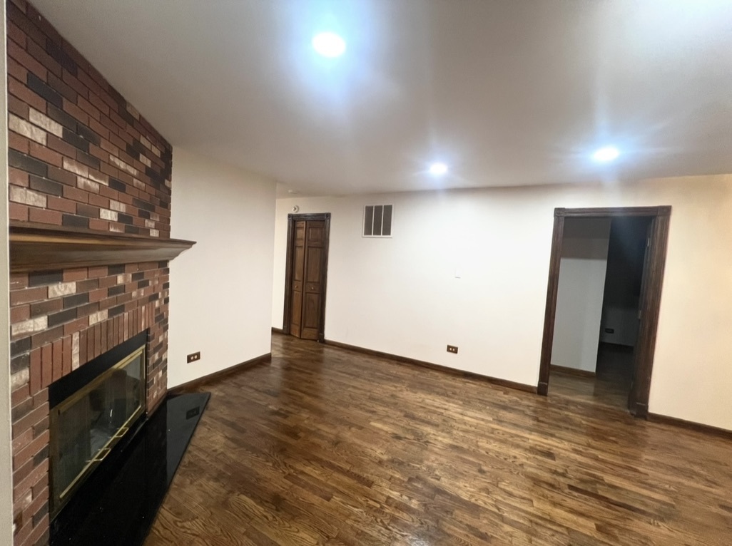 3529 Carpenter Street Steger, IL 60475 - Photo 10 of 20 an empty room with wooden floor fireplace and windows