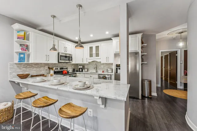 a kitchen with stainless steel appliances granite countertop a kitchen island a stove a table and chairs