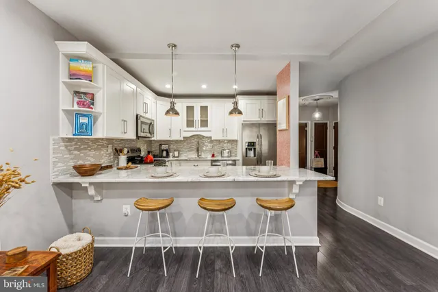 a kitchen with stainless steel appliances granite countertop a dining table chairs and white cabinets