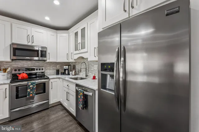 a kitchen with stainless steel appliances granite countertop a refrigerator a stove a sink and a microwave