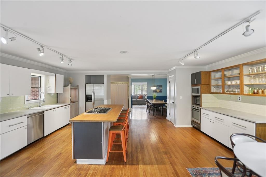3224 Kensington Road Avondale Estates, GA 30002 - Photo 10 of 59 a large open kitchen with stainless steel appliances granite countertop a stove a refrigerator a dining table and chairs with wooden floor