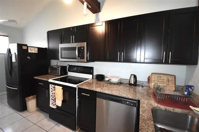 a kitchen with stainless steel appliances granite countertop a refrigerator a stove a sink and a microwave