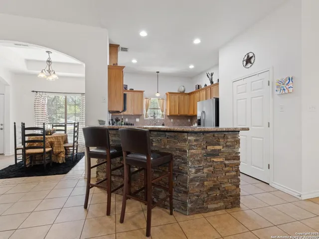 a kitchen with kitchen island granite countertop a table chairs sink and cabinets