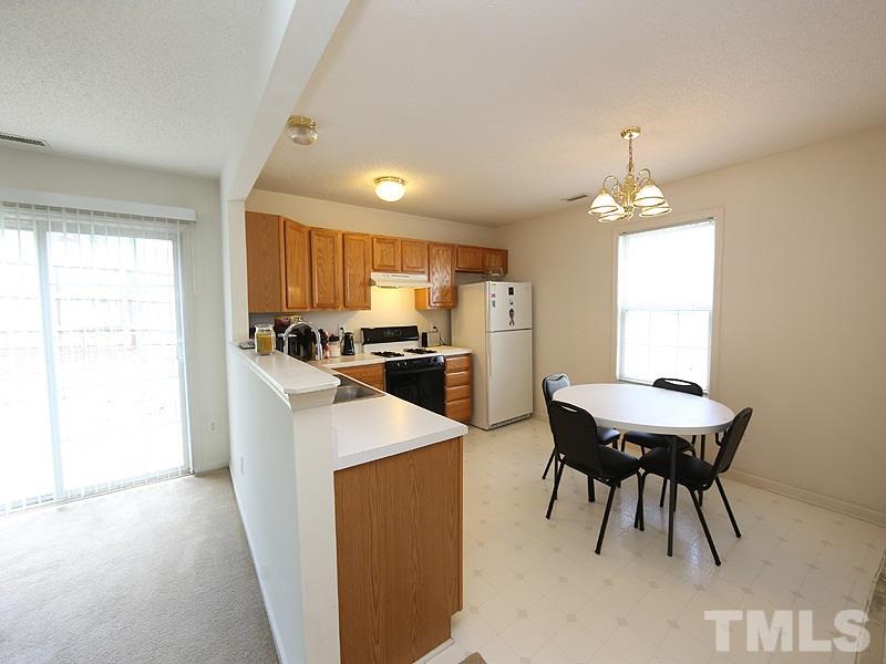 4205 Toccopola Street Raleigh, NC 27604 - Photo 10 of 24 a kitchen with a table chairs refrigerator and cabinets