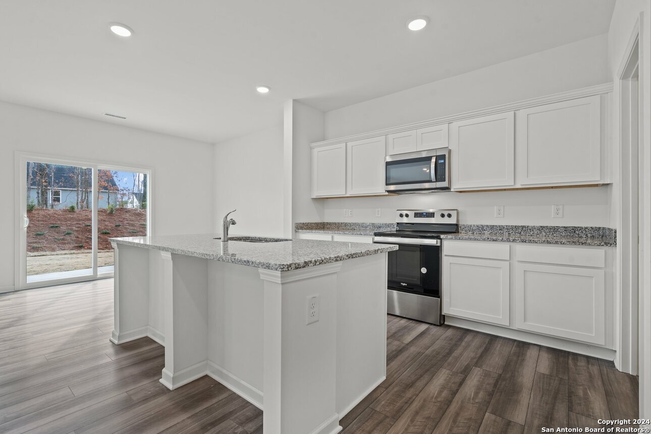 1428 Almeda Road Seguin, TX 78155 - Photo 3 of 17 a kitchen with granite countertop white cabinets and white appliances