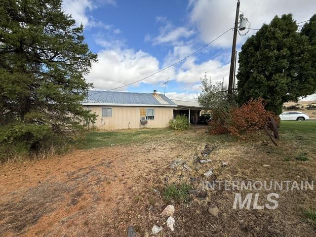555 Cemetery Road Cambridge, ID 83610 - Photo 20 of 41 Metal roof, siding exterior, mature evergreen trees, and an attached carport