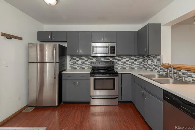 a kitchen with granite countertop wooden floors stainless steel appliances and cabinets