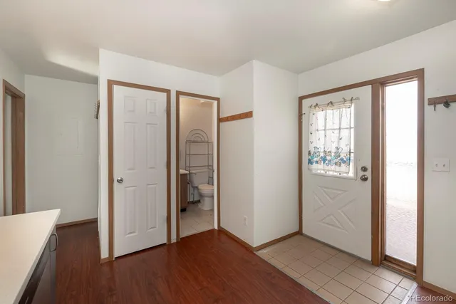 an empty room with wooden floor closet and windows