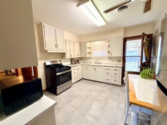 a kitchen with stainless steel appliances granite countertop a stove top oven a sink a counter space and cabinets