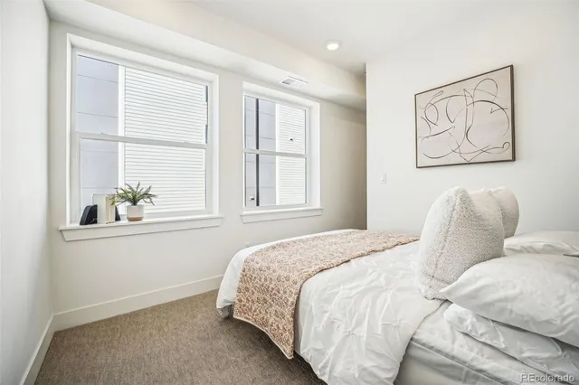 a bedroom with a bed and a window with chair