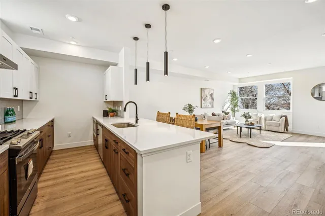 a kitchen with counter top space a sink stove and white cabinets