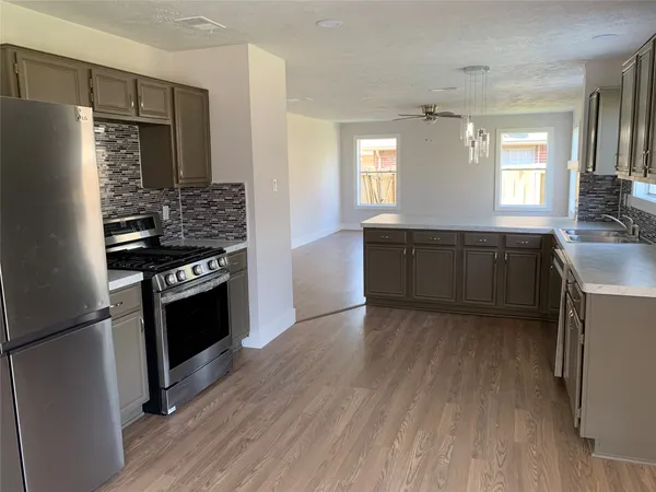 a kitchen with stainless steel appliances granite countertop a refrigerator a stove and a sink