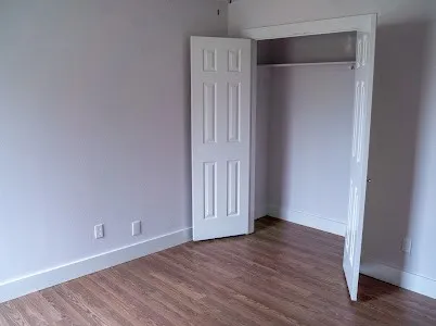a view of an empty room with wooden floor and closet
