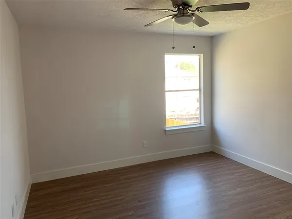 an empty room with a window and a ceiling fan