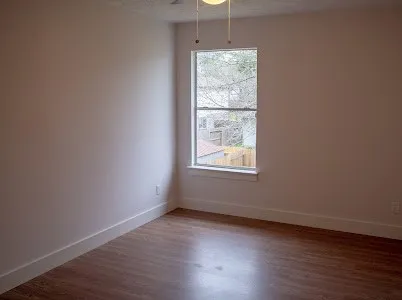 an empty room with wooden floor and windows