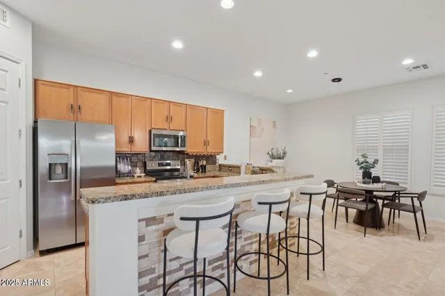 a kitchen with stainless steel appliances granite countertop a table chairs microwave and sink