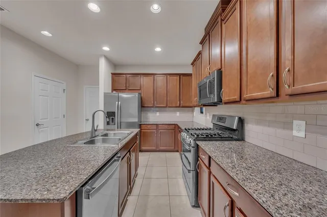 a kitchen with granite countertop stainless steel appliances granite countertop a sink a stove and a wooden cabinets