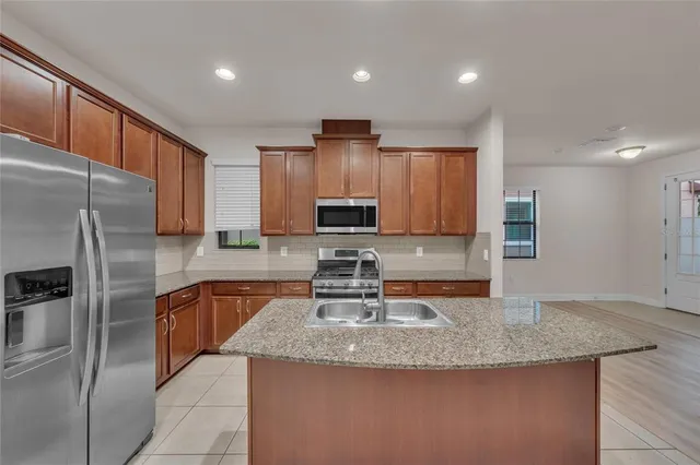 a kitchen with stainless steel appliances granite countertop a sink refrigerator and cabinets