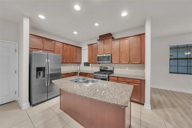 a kitchen with granite countertop kitchen island stainless steel appliances a refrigerator sink stove microwave and cabinets