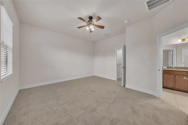 an empty room with chandelier fan and windows