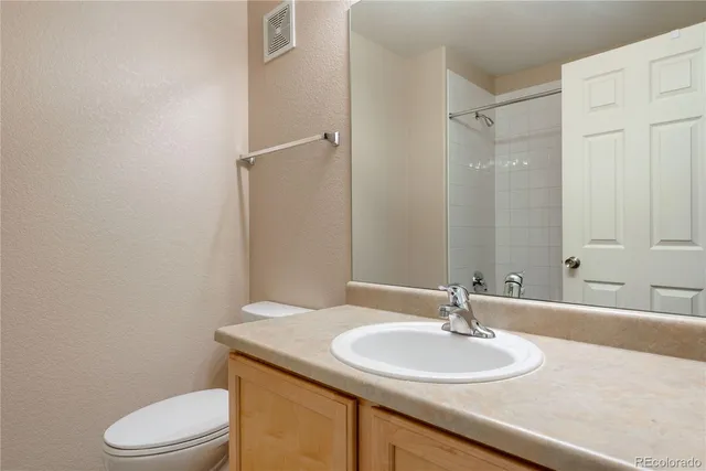 a bathroom with a granite countertop sink toilet and a mirror