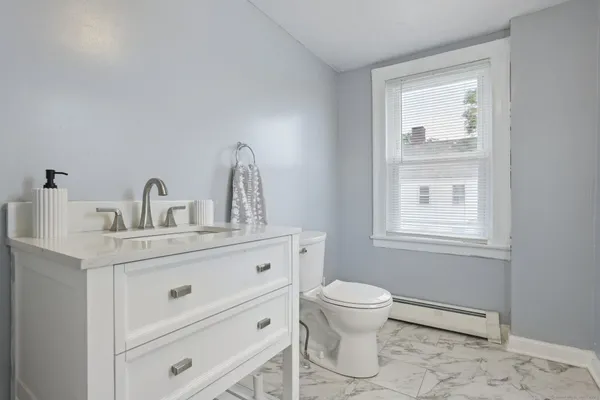 a bathroom with a toilet a sink a mirror and a window