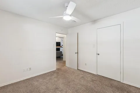 an empty room with closet and a ceiling fan