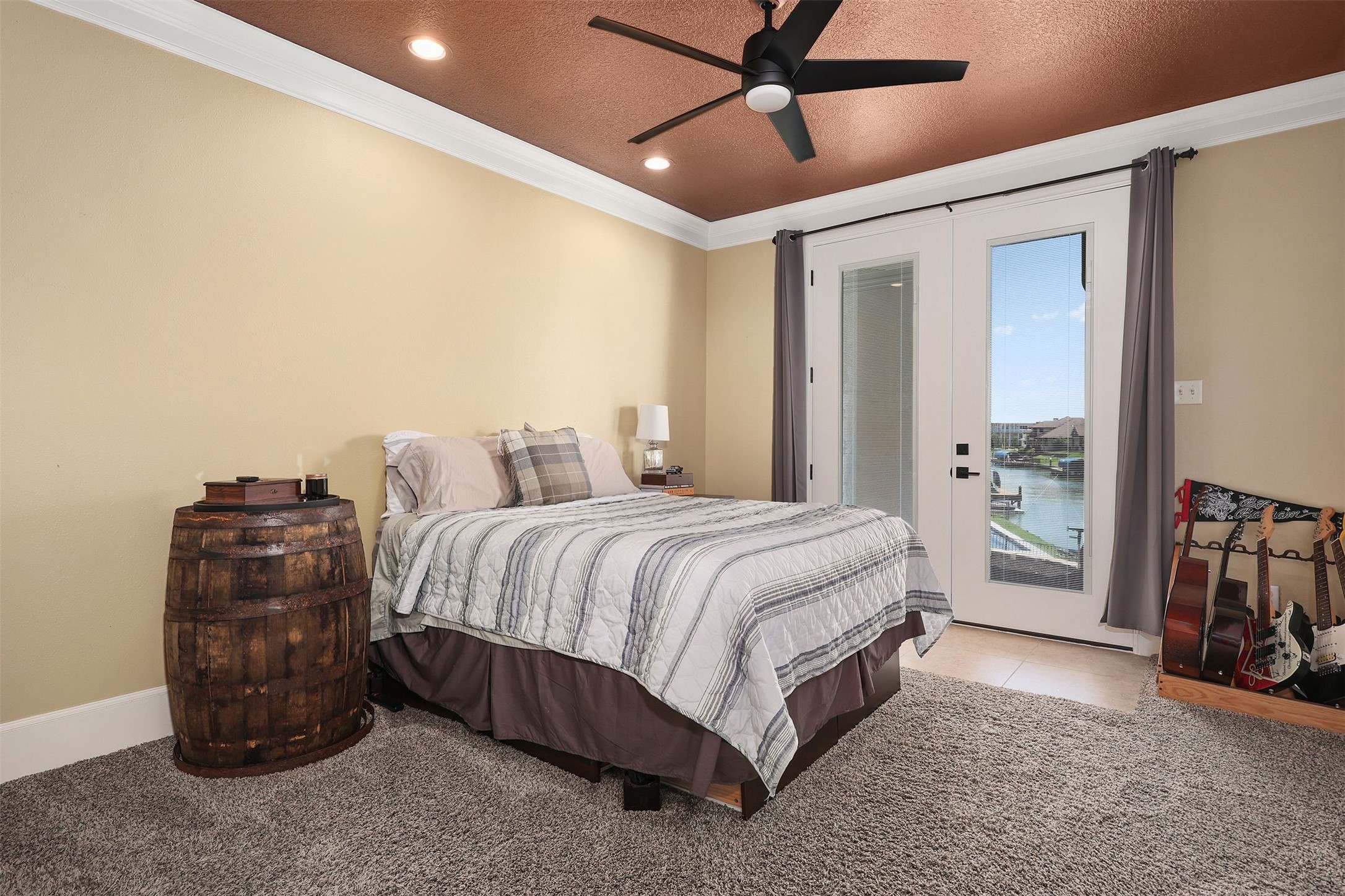10896 Decatur Street Willis, TX 77318 - Photo 42 of 50 This cozy bedroom offers a warm, inviting atmosphere with a rustic barrel nightstand, plush carpeting, and French doors that open to a scenic water view, flooding the space with natural light and serenity; a ceiling fan ensures comfort, while a charming guitar nook adds unique character.