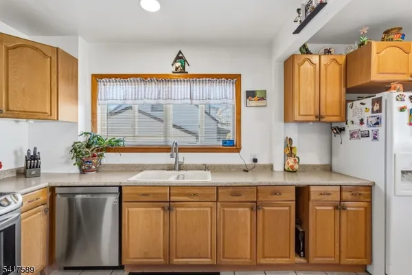 a kitchen with stainless steel appliances granite countertop a sink a refrigerator and a granite counter tops with a window