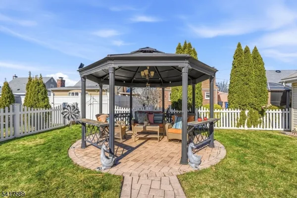 a view of a patio with a table and chairs under an umbrella with a small yard