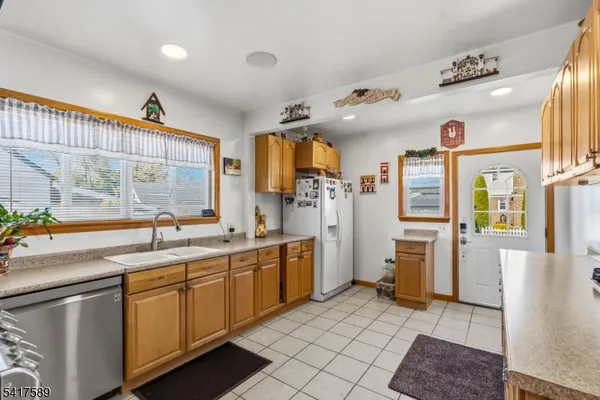 a large kitchen with stainless steel appliances kitchen island granite countertop a refrigerator and a sink