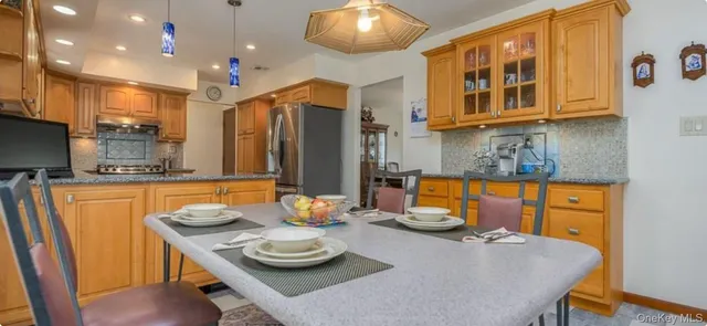 a kitchen with stainless steel appliances kitchen island granite countertop a table and chairs in it