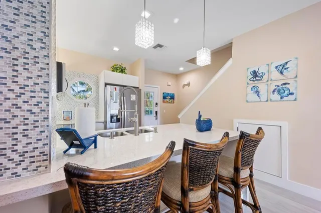 a kitchen with stainless steel appliances a dining table chairs and a refrigerator