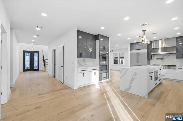 a large white kitchen with stainless steel appliances kitchen island a large counter top and a sink