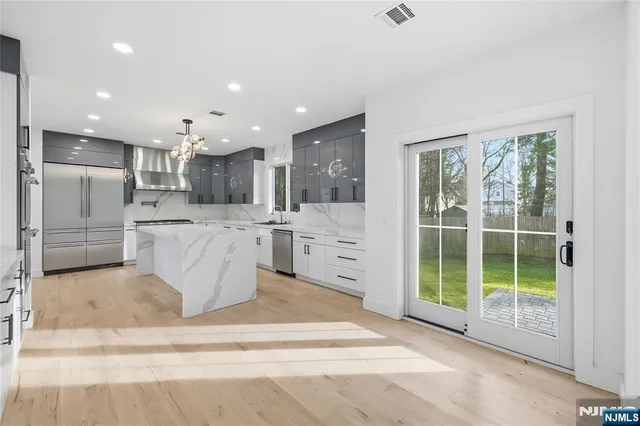 a large white kitchen with a large window and stainless steel appliances