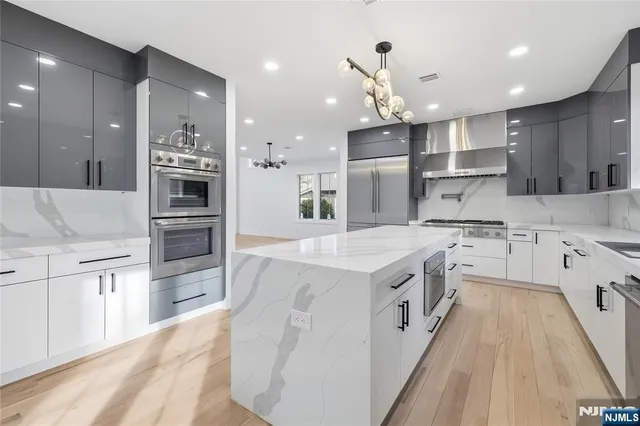 a large kitchen with stainless steel appliances kitchen island granite countertop a large center island and a stove top oven