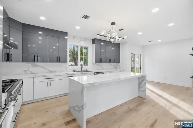 a large white kitchen with a sink and chandelier