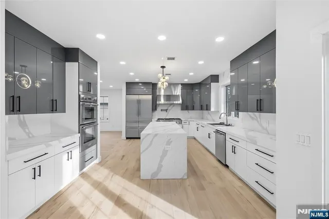 a large white kitchen with a large kitchen island white cabinets and stainless steel appliances