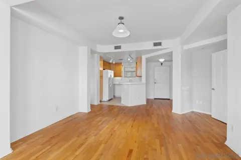 a view of empty room with wooden floor and fan