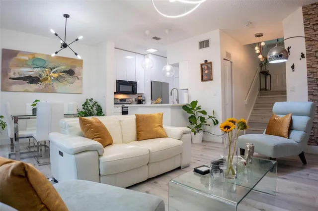a living room with furniture kitchen view and a chandelier