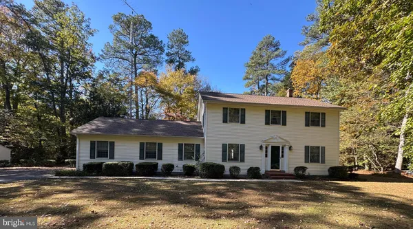 a view of a white house with a large tree and next to a yard