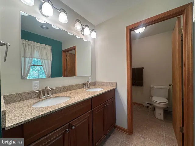 a bathroom with a granite countertop sink toilet and mirror